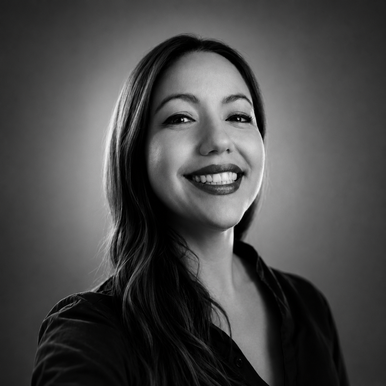 Portrait of a woman with brown hair on a flat gray background.