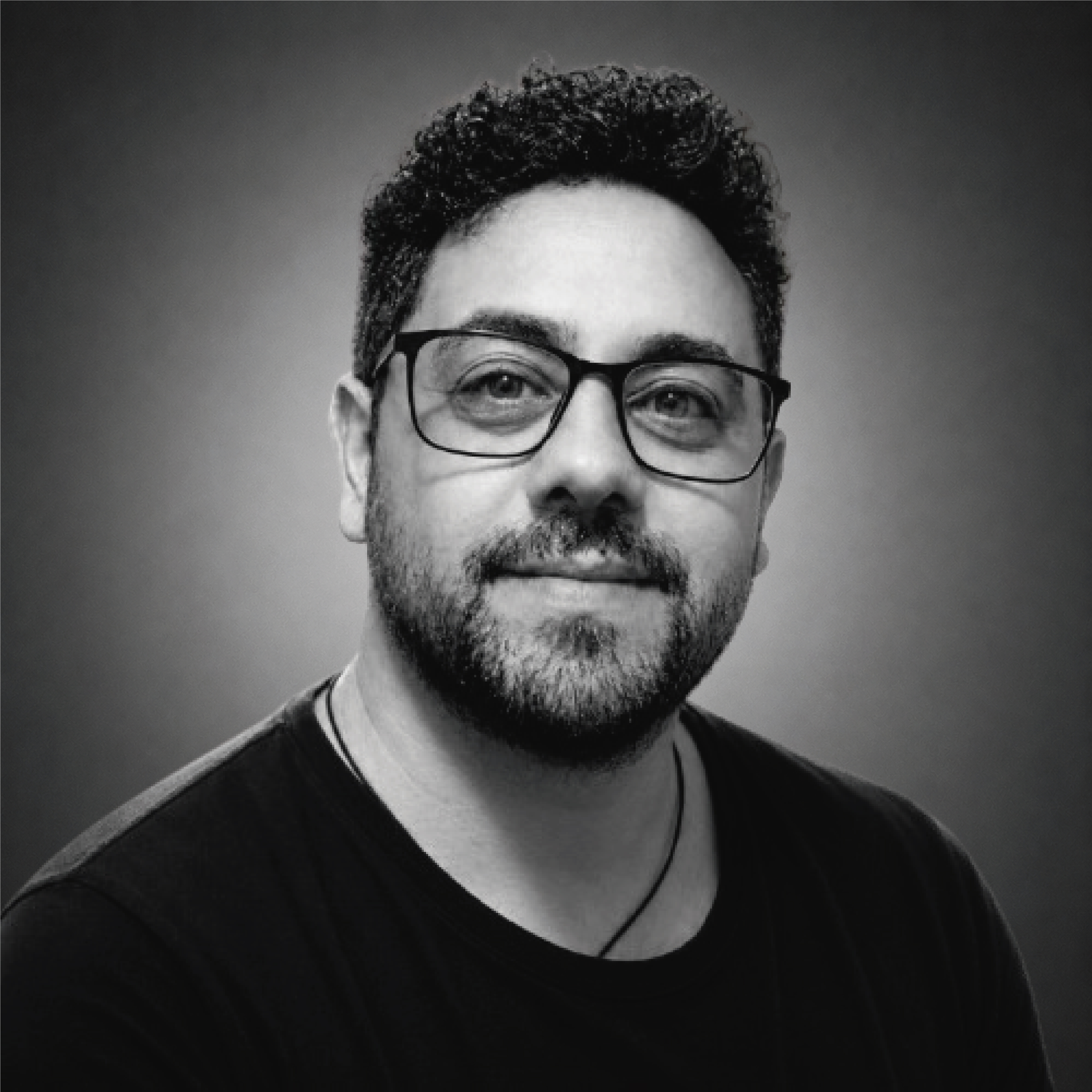 Portrait of a man with brown hair and glasses on a flat gray background.